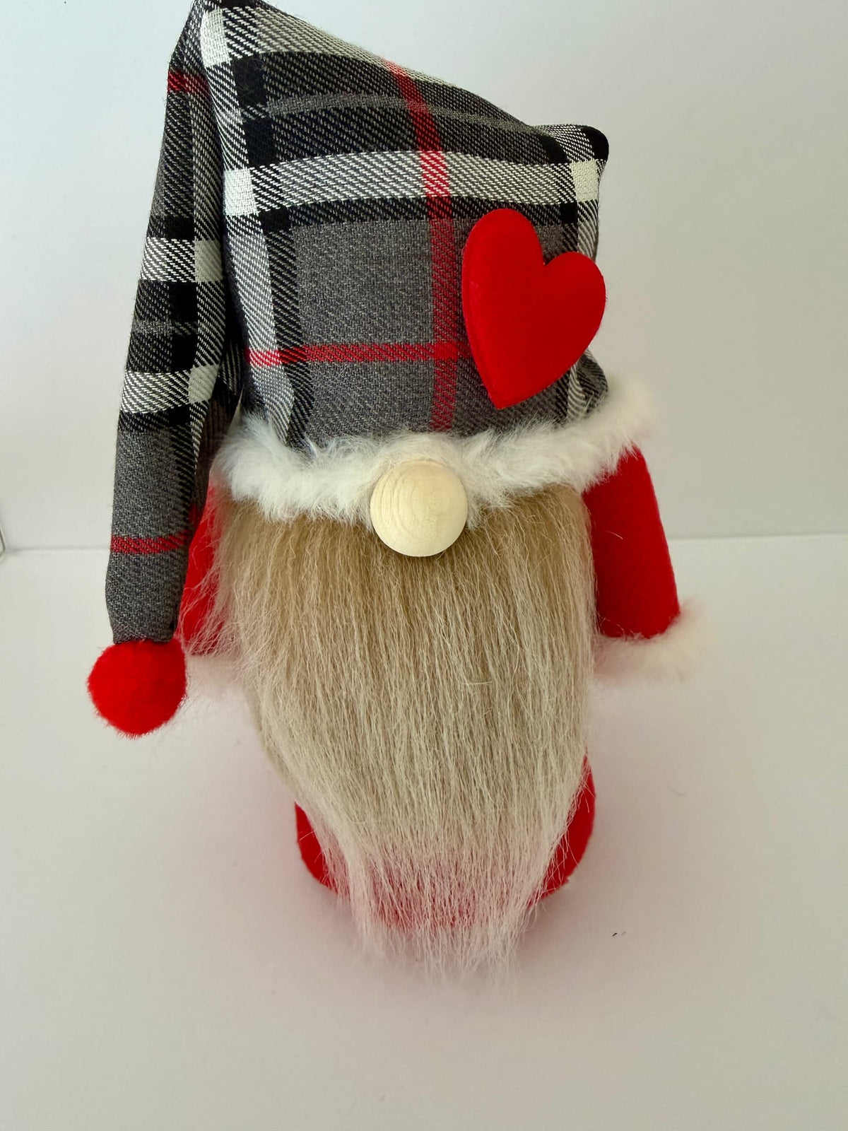A Scottish Dreamer gnome by Northern Nomes with a gray, black, and red plaid nightcap style hat featuring a red heart accent, a long beige faux-fur beard, and red clothing, photographed against a plain white background.