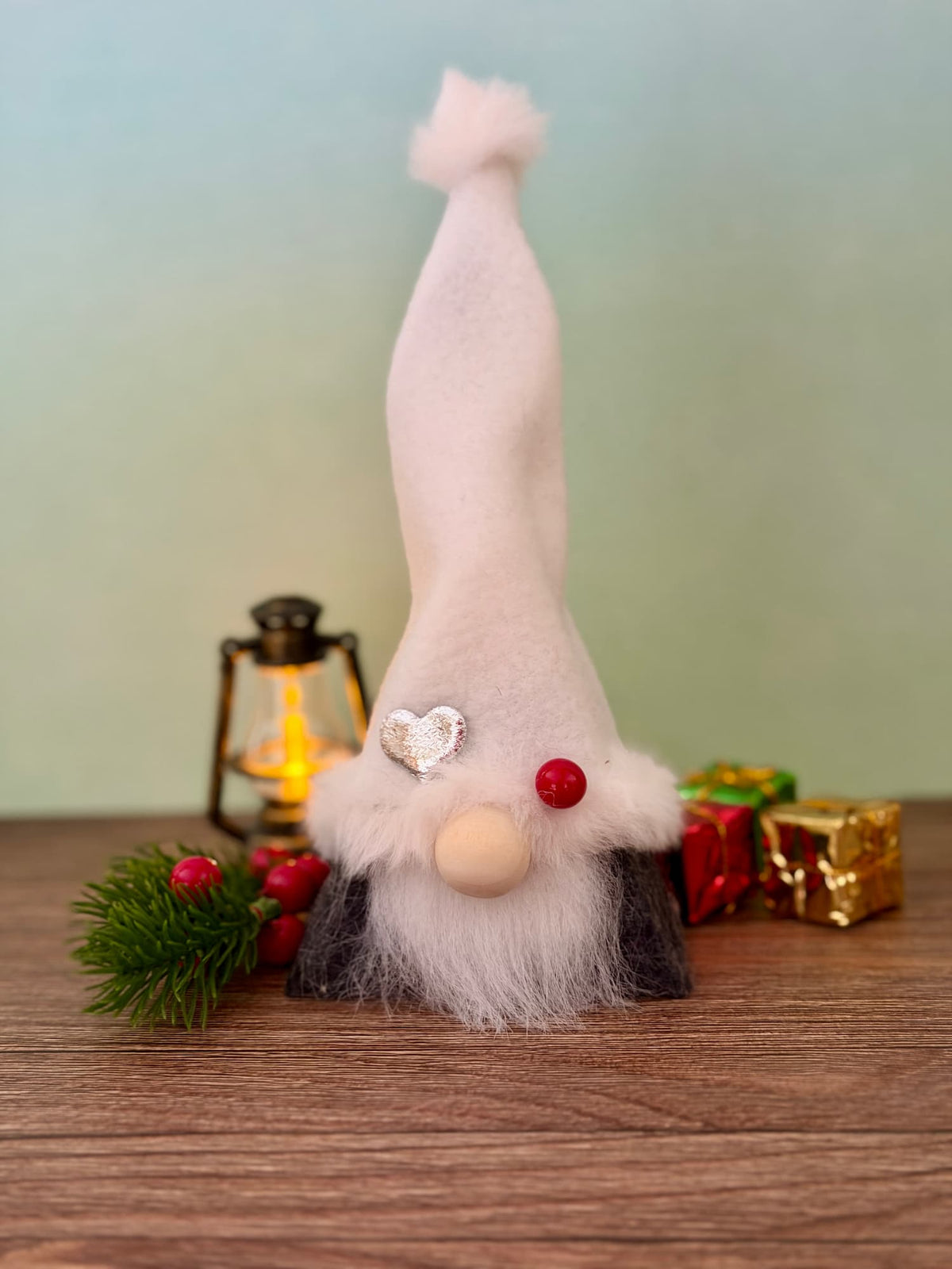 Christmas Gnome with a tall white fleece hat and grey body, wooden button nose, white faux fur beard and silver heart embellishment. Handmade by Northern Nomes from the Yuletide Folk collection.